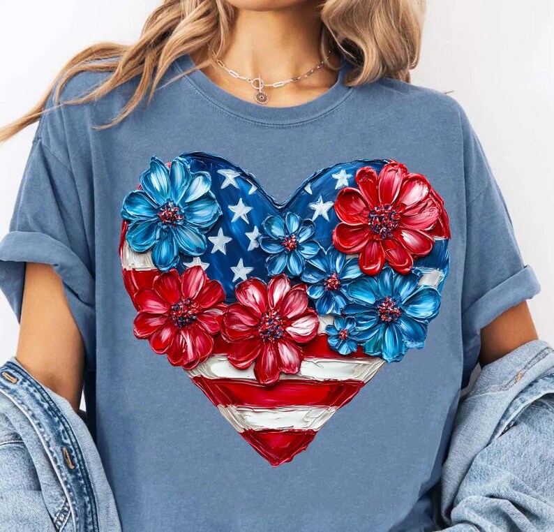 May include: A blue t-shirt with a red, white, and blue heart-shaped design. The heart is made up of painted flowers and an American flag.