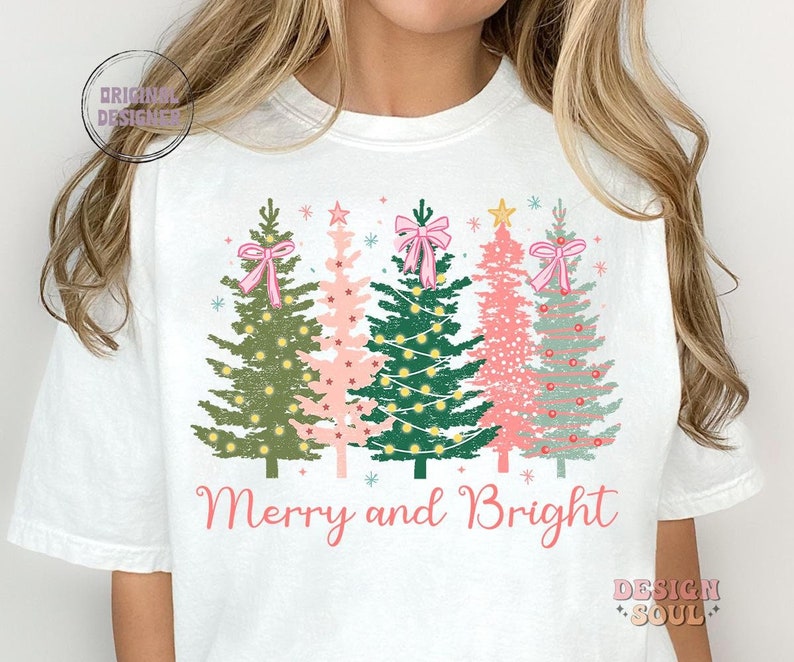 May include: White t-shirt with a Christmas tree design and the text "Merry and Bright".