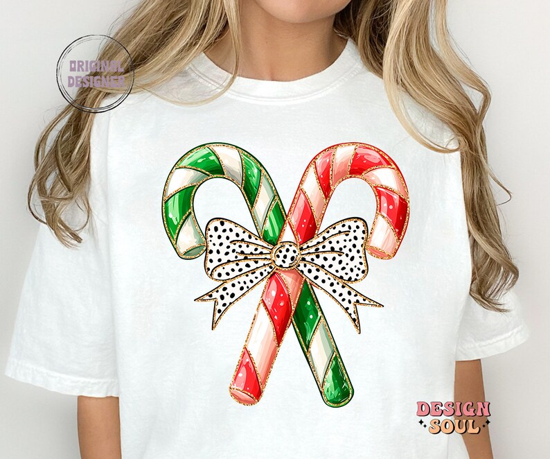 May include: White t-shirt with a graphic of two candy canes tied together with a black and white polka dot bow. The candy canes are red and white and green and white.