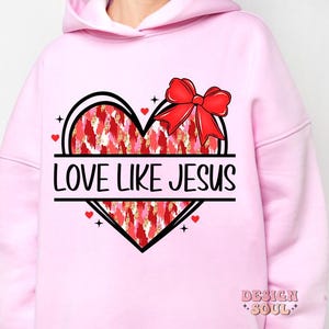 May include: Pink hoodie with a graphic of a red heart with a bow on top and the text "Love Like Jesus".