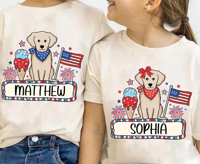 Pu&ograve; includere: Due magliette bianche a tema patriottico. Le magliette presentano un labrador retriever giallo, una bandiera americana, fuochi d'artificio e coni gelato. Una maglietta dice "Matthew" e l'altra dice "Sophia".