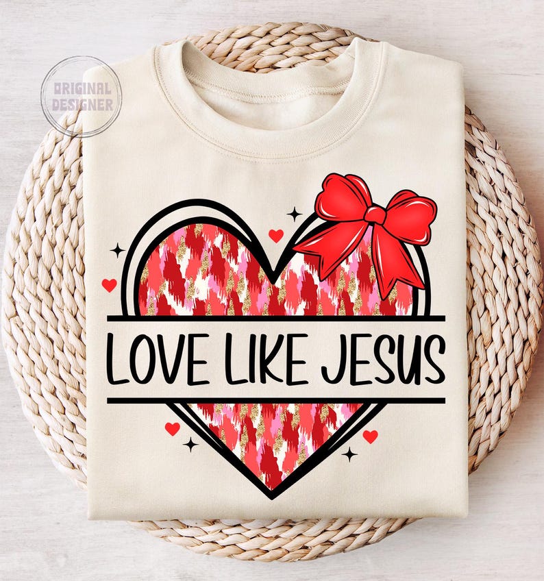 May include: A beige sweatshirt with a red and pink heart design and the text "LOVE LIKE JESUS". The heart has a red bow on top.