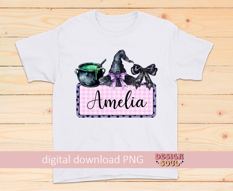 May include: A white t-shirt with a pink and purple gingham and polka dot design featuring a witch's hat, cauldron, and a bow. The text "Amelia" is on the design.