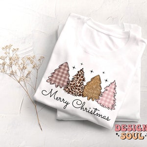May include: White sweatshirt with a pink, brown, and gold Christmas tree design. The text "Merry Christmas" is written in black cursive below the trees.