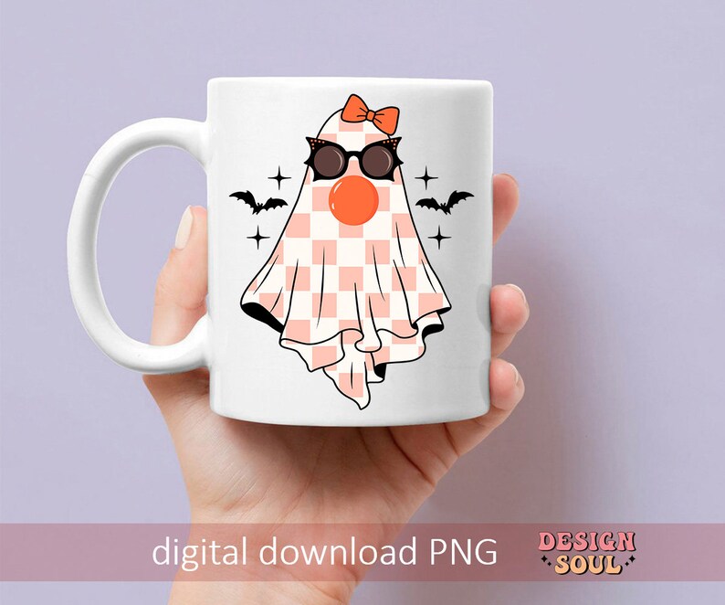 May include: A white ceramic mug with a pink and white checkered ghost wearing black sunglasses and a pink bow. The ghost has a red nose and is surrounded by black bats and stars.