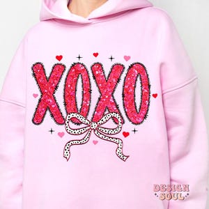 May include: Pink hoodie with a sparkly pink and black "XOXO" design with a black and white polka dot bow.