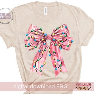 May include: A beige t-shirt with a pink bow with colorful lights on it. The bow is centered on the shirt. The text "digital download PNG" is at the bottom of the shirt.