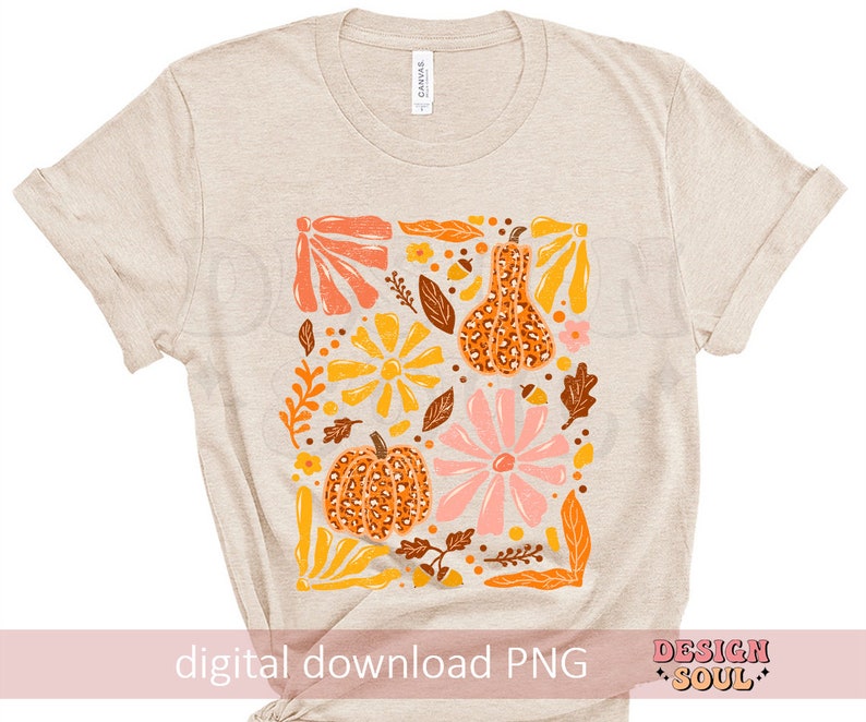 May include: A beige t-shirt with a digital print of a floral design featuring pumpkins and gourds in shades of orange, yellow, pink, and brown. The design is surrounded by leaves and vines.