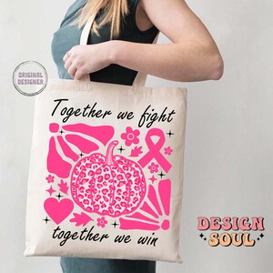 Peut inclure: Un sac fourre-tout blanc avec du texte et des graphismes roses. Le texte dit "Ensemble nous luttons, ensemble nous gagnons". Les graphismes comprennent un ruban rose, une citrouille rose &agrave; imprim&eacute; l&eacute;opard et d'autres formes abstraites roses. Le sac est tenu par une personne.
