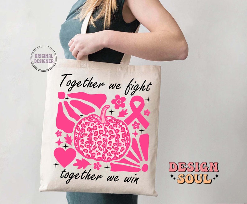 Peut inclure: Un sac fourre-tout blanc avec du texte et des graphismes roses. Le texte dit "Ensemble nous luttons, ensemble nous gagnons". Les graphismes comprennent un ruban rose, une citrouille rose &agrave; imprim&eacute; l&eacute;opard et d'autres formes abstraites roses. Le sac est tenu par une personne.
