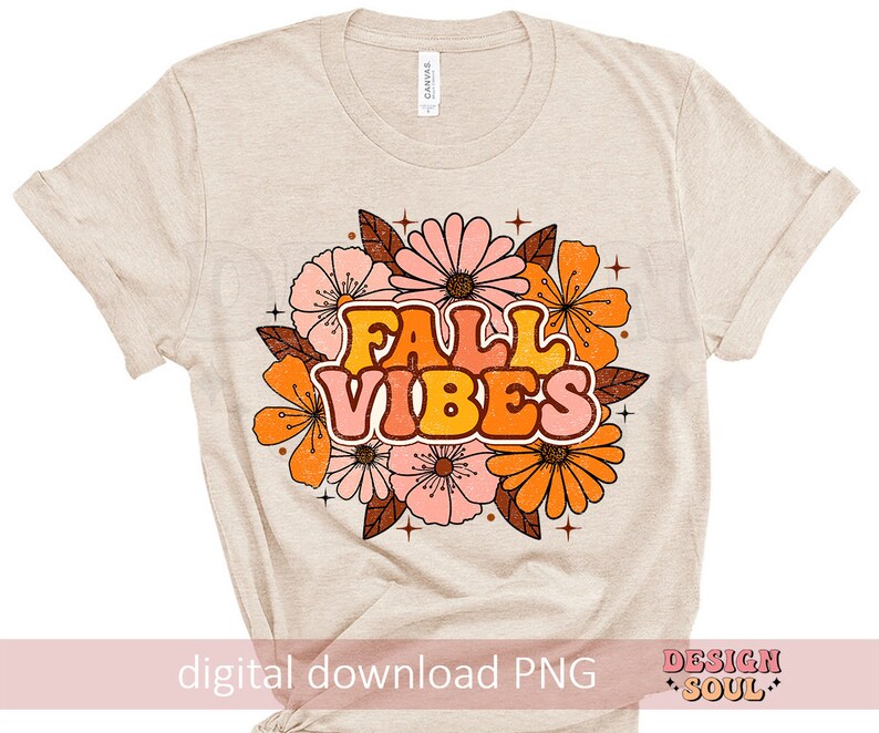 May include: A beige t-shirt featuring a graphic design of autumn-coloured flowers and the text "Fall Vibes" in a retro font.