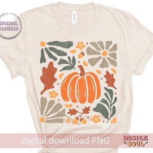 May include: A beige t-shirt featuring a digital print of a pumpkin and autumn foliage in shades of orange, green, brown, and grey. The design includes a stylised pumpkin, leaves, and flowers. The text "digital download PNG" is at the bottom of the shirt.