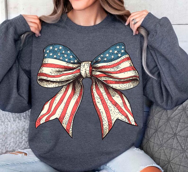 Peut inclure: Un sweat-shirt gris fonc&eacute; avec un grand n&oelig;ud rouge, blanc et bleu imprim&eacute; sur le devant. Le n&oelig;ud est dans le style du drapeau am&eacute;ricain.