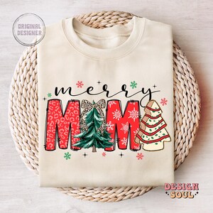 May include: A cream-colored sweatshirt with the text "merry mama" in red, green, and white. The text is decorated with a Christmas tree, snowflakes, and leopard print.