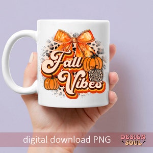 May include: White ceramic mug with a fall-themed design. The design features a large orange bow with glitter, pumpkins, and the text "Fall Vibes" in a retro font.