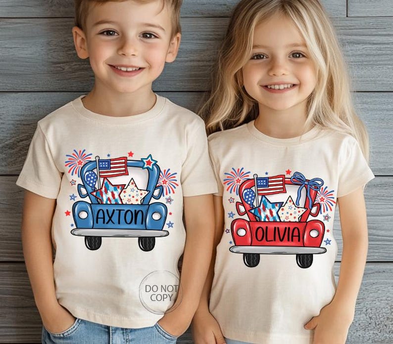 May include: Two children wearing cream-colored t-shirts with a patriotic design. The shirts feature a cartoon truck carrying stars, fireworks, and an American flag. One shirt says "AXTON" and the other says "OLIVIA".