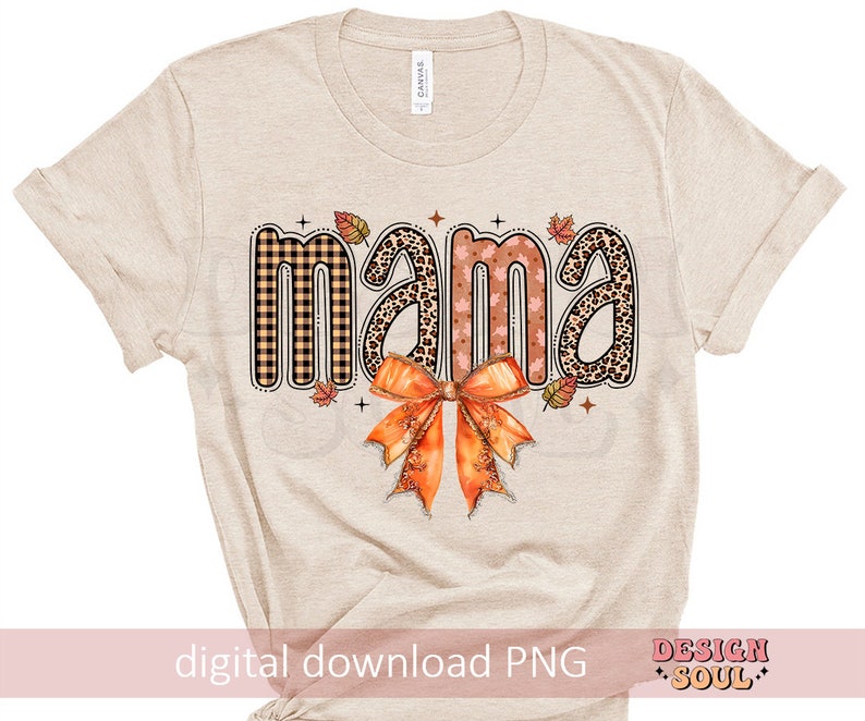 May include: A beige t-shirt with the word "mama" in a fall-themed design. The word is made up of different patterns, including plaid, leopard print, and floral. A large orange bow is below the word.