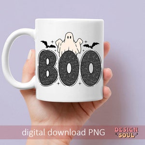 May include: White ceramic mug with a black and white design of a ghost and bats with the word "BOO" in black glitter letters.