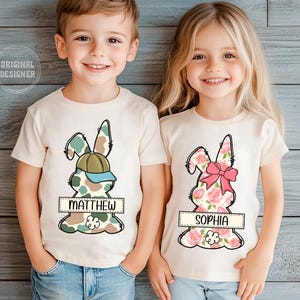 May include: Two children wearing white t-shirts with a camouflage bunny design for the boy and a floral bunny design for the girl. The boy's shirt says "Matthew" and the girl's shirt says "Sophia".