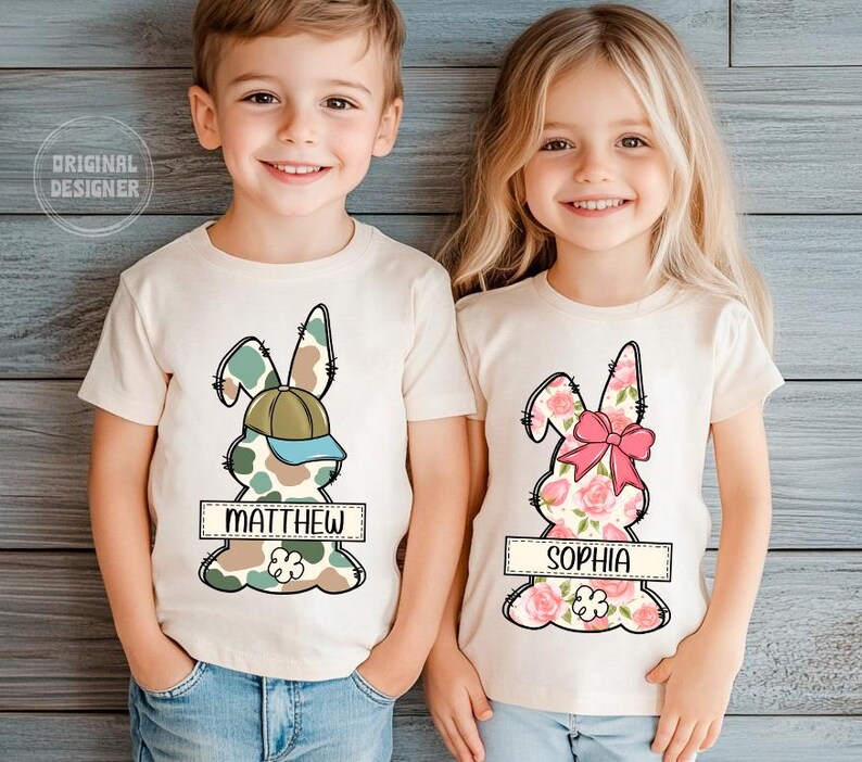 May include: Two children wearing white t-shirts with a camouflage bunny design for the boy and a floral bunny design for the girl. The boy's shirt says "Matthew" and the girl's shirt says "Sophia".