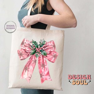 May include: A white tote bag with a pink bow and holly design. The bag has the text "DESIGN SOUL" printed on the bottom right corner.