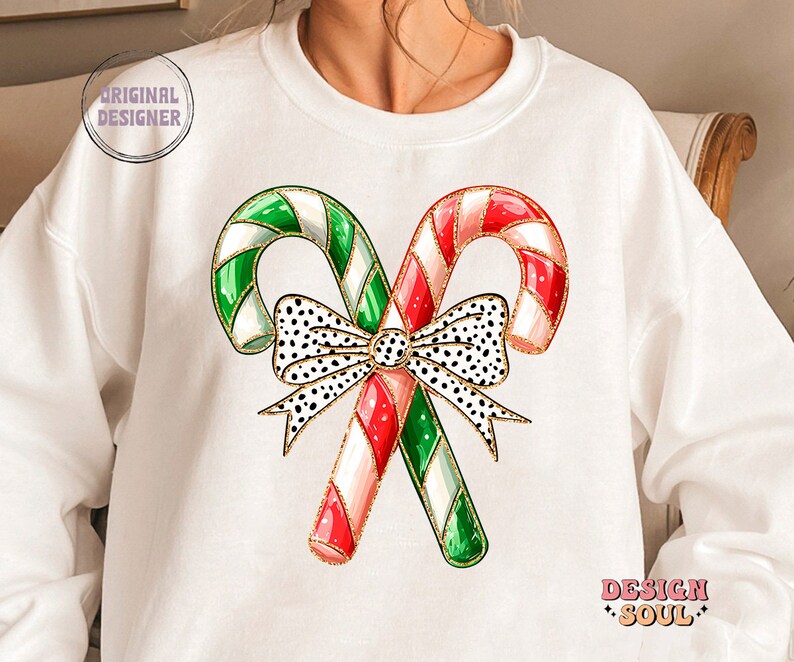 May include: White sweatshirt with a graphic of two candy canes tied together with a black and white polka dot bow. The candy canes are red and white and green and white.