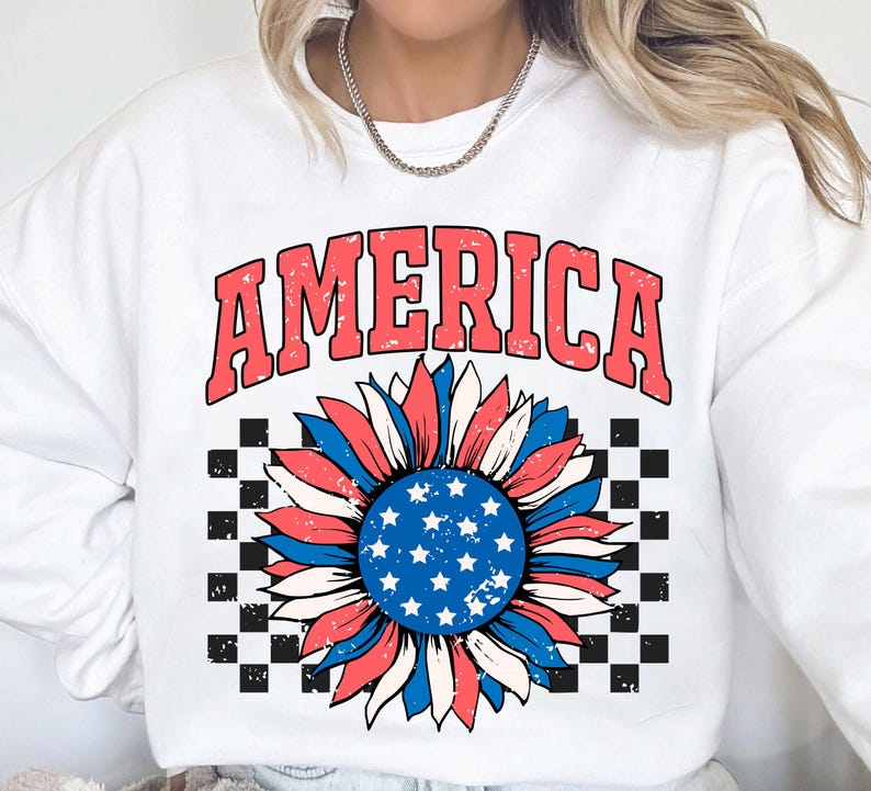 May include: White sweatshirt with a red, white, and blue sunflower graphic and the word "AMERICA" in red letters. The sunflower has a checkered background.