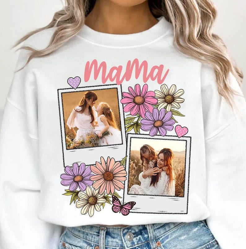 May include: White sweatshirt with the word "Mama" in pink script, decorated with floral graphics and two framed photos. The photos show a mother and child. A butterfly and heart accents complete the design.