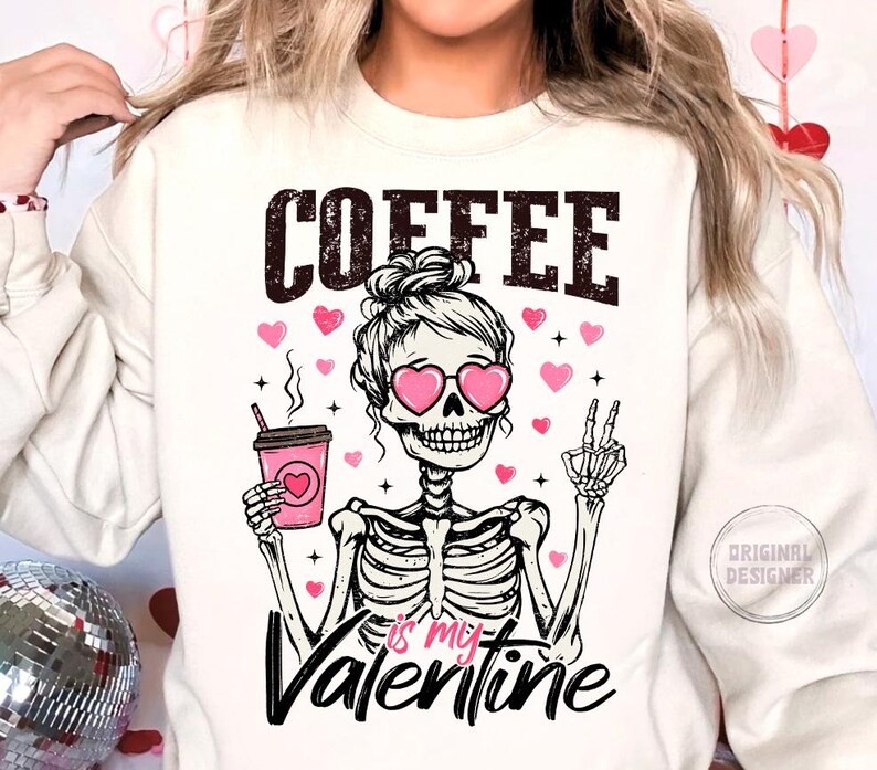 May include: White sweatshirt with a pink skeleton wearing heart-shaped sunglasses and holding a cup of coffee. The text "COFFEE is my VALENTINE" is printed on the shirt.