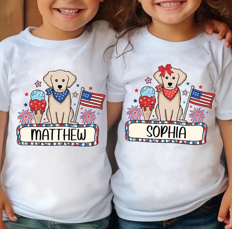 Pu&ograve; includere: Due magliette bianche a tema patriottico. Una maglietta presenta un cane giallo con una bandana rosso, bianco e blu, un cono gelato, fuochi d'artificio e il nome "MATTHEW". L'altra maglietta presenta un cane giallo con un fiocco rosso, un cono gelato, fuochi d'artificio e il nome "SOPHIA".