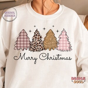 May include: White sweatshirt with a pink, gold, and leopard print Christmas tree design and the text "Merry Christmas".