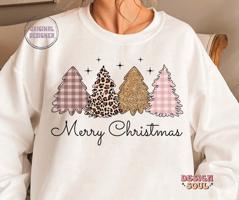 May include: White sweatshirt with a pink, gold, and leopard print Christmas tree design and the text "Merry Christmas".
