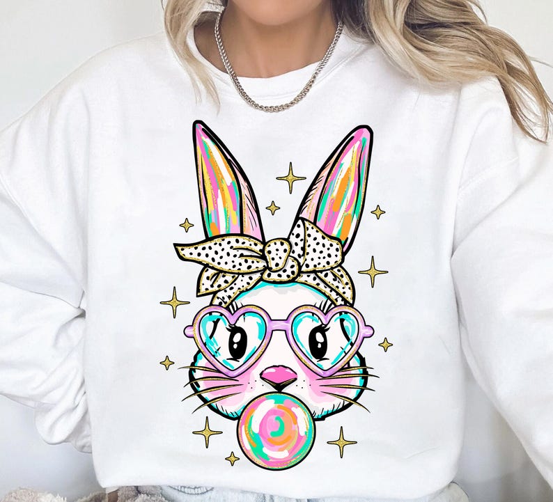 May include: White sweatshirt with a colorful cartoon bunny wearing heart-shaped sunglasses and a polka dot headband. The bunny is blowing a bubblegum bubble.