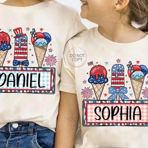 May include: Two cream-colored t-shirts with matching patriotic ice cream cone designs. One shirt says "DANIEL" and the other says "SOPHIA" in a red and blue plaid frame. The ice cream cones are red, white, and blue.