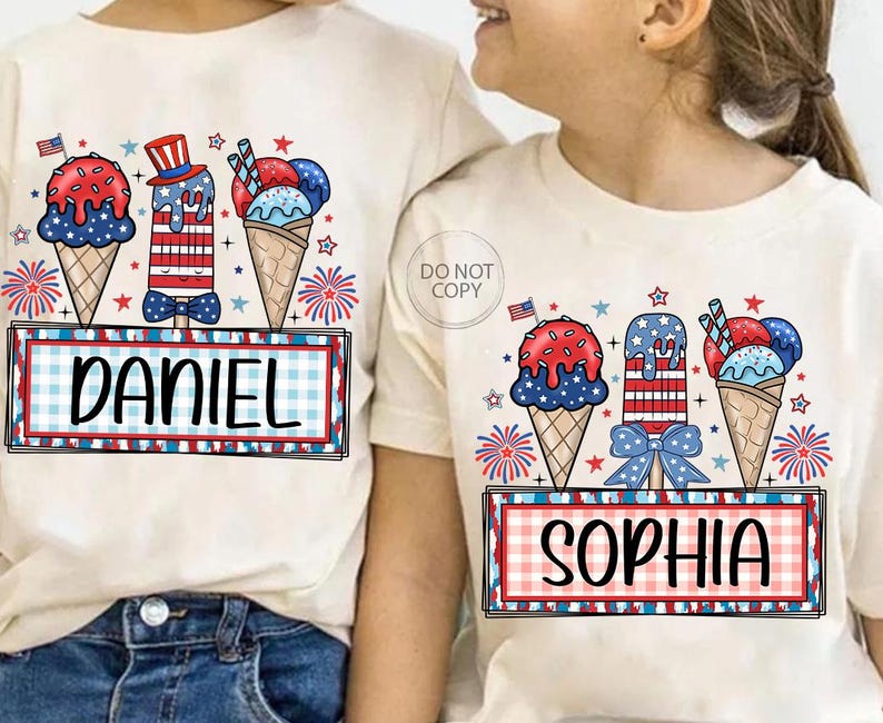 May include: Two cream-colored t-shirts with matching patriotic ice cream cone designs. One shirt says "DANIEL" and the other says "SOPHIA" in a red and blue plaid frame. The ice cream cones are red, white, and blue.