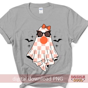 May include: A gray t-shirt with a pink and white checkered ghost wearing sunglasses and a pink bow. The ghost has a red nose and is surrounded by black bats and stars. The text "digital download PNG" and "DESIGN SOUL" are at the bottom of the shirt.