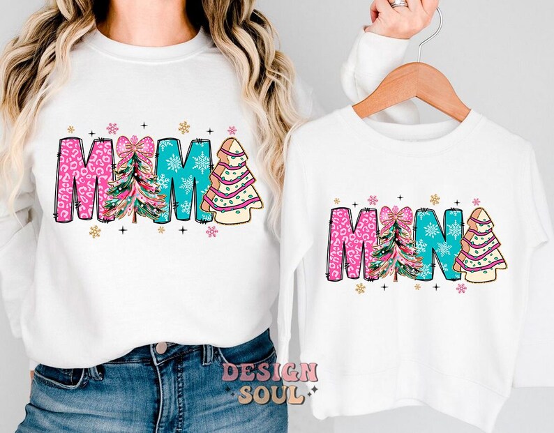 May include: White long-sleeve shirts with a Christmas tree design and the words "MAMA" and "MINA" in pink, blue, and green.