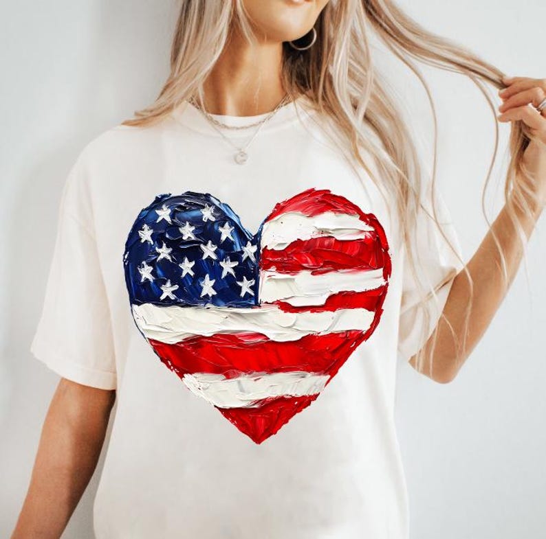 Pu&ograve; includere: Maglietta bianca con una bandiera americana dipinta a forma di cuore.