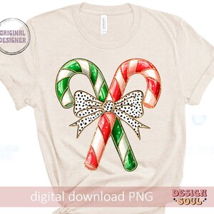 May include: A digital download of a graphic design featuring two candy canes crossed over each other with a black and white polka dot bow with gold accents. The candy canes are red and white and green and white.
