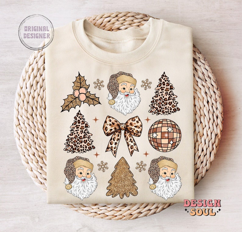 May include: A beige sweatshirt with a festive Christmas design featuring Santa Claus, Christmas trees, a disco ball, and a bow. The design is in a leopard print and gold glitter pattern.