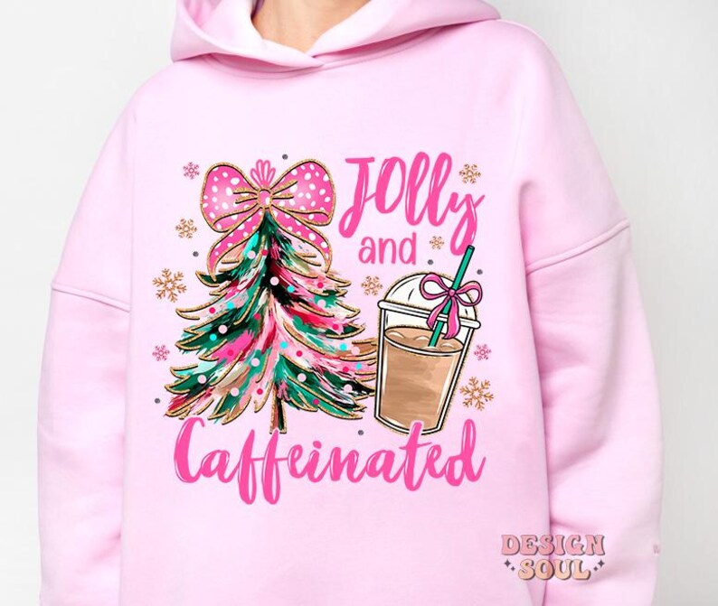 May include: Pink hoodie with a Christmas tree and a cup of coffee graphic. The text on the hoodie says "Jolly and Caffeinated".