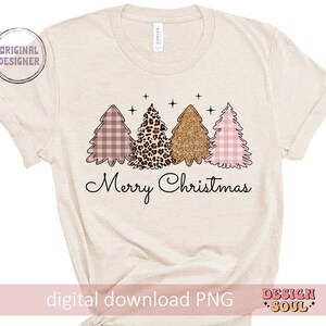 May include: A beige t-shirt with a design of three Christmas trees. The trees are pink and white gingham, leopard print, and gold glitter. The text "Merry Christmas" is below the trees.