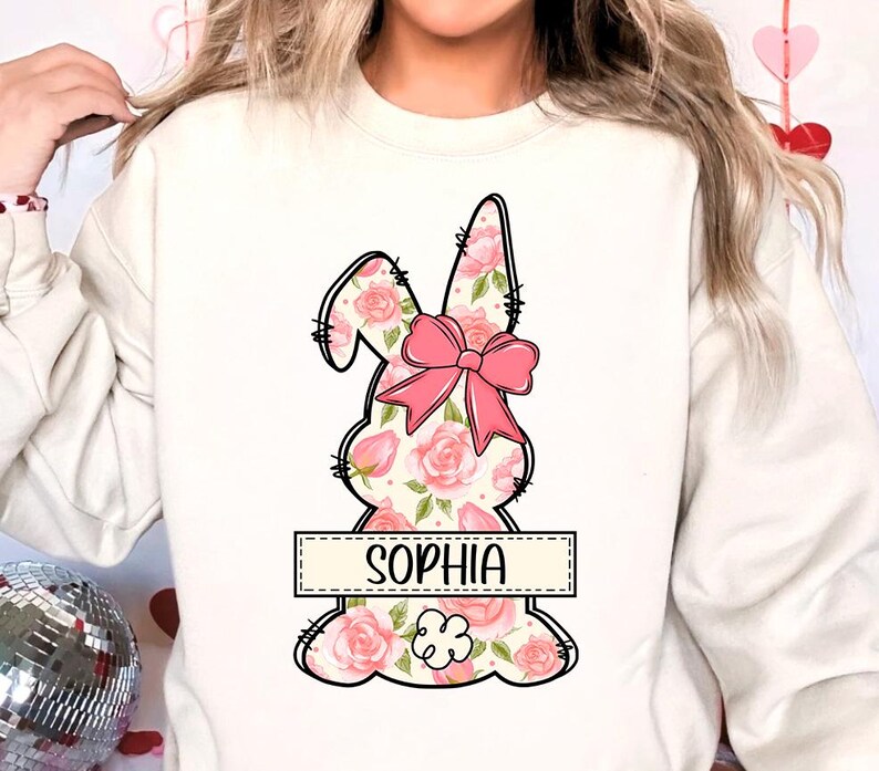 May include: White sweatshirt with a pink floral bunny design and the name "Sophia" printed below it.