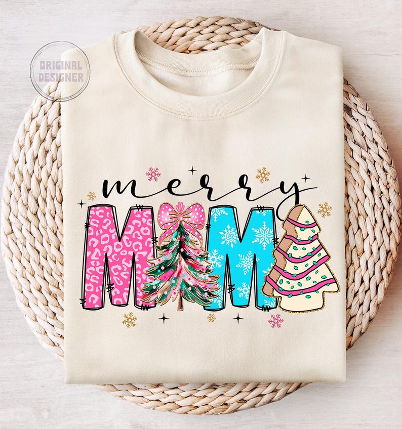 Peut inclure: Un sweat-shirt cr&egrave;me avec le texte "merry mama" en lettres noires. Les lettres sont d&eacute;cor&eacute;es de sapins de No&euml;l roses, bleus et verts.