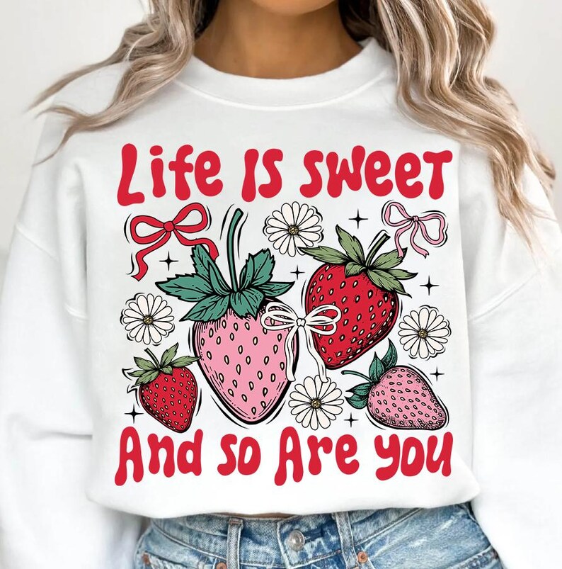 May include: White sweatshirt with a red graphic that says "Life is sweet and so are you". The graphic also features strawberries, flowers, and bows.
