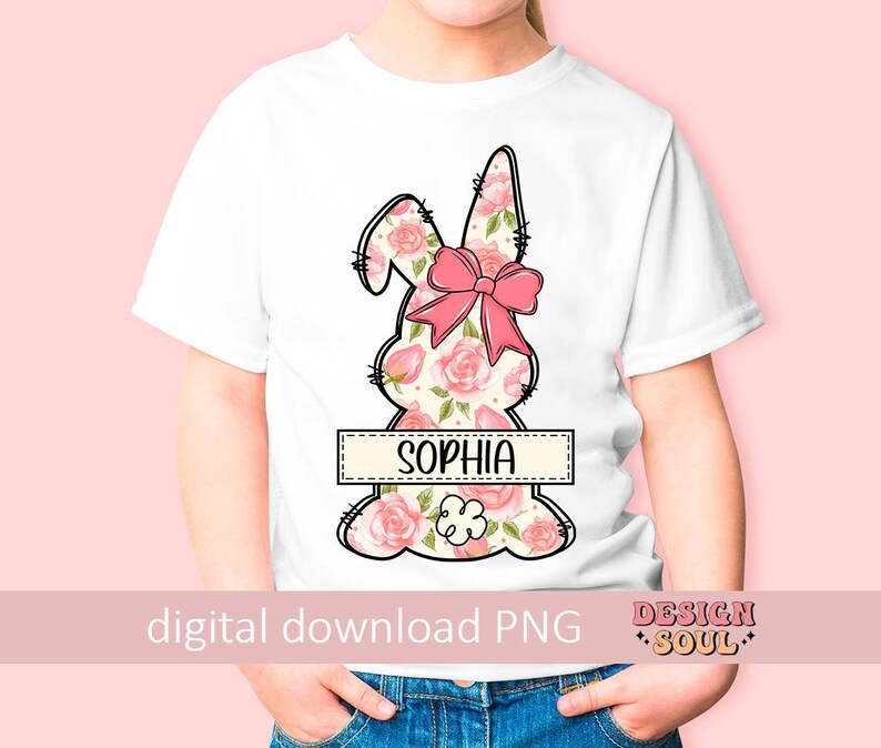 May include: A white t-shirt with a pink floral bunny design and the name "Sophia" printed on a banner. The bunny has a pink bow.