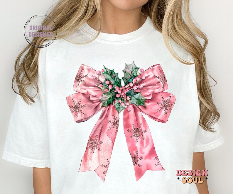 May include: A white t-shirt with a pink bow with holly and berries. The bow has a sparkly, watercolor effect.