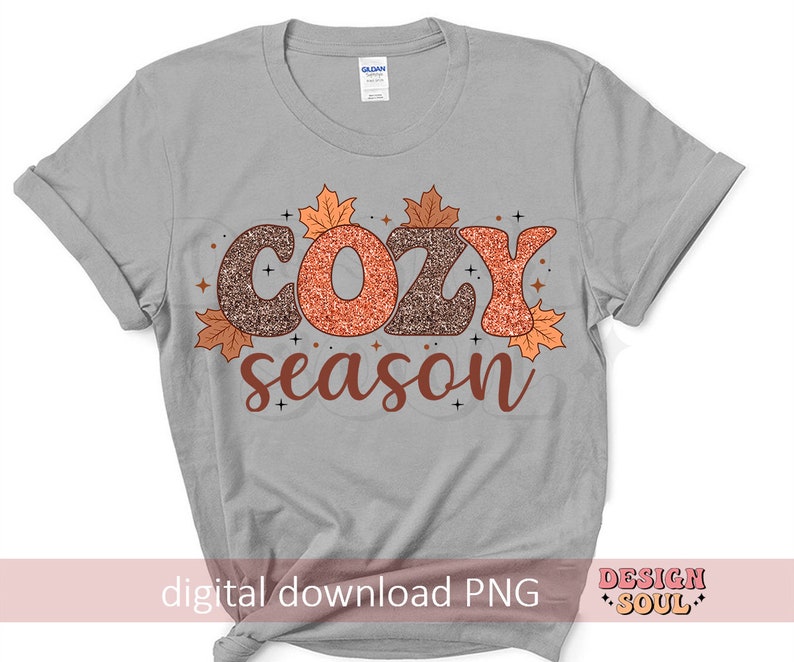 May include: A light gray t-shirt with the words "COZY season" in a fall-themed design. The word "COZY" is in glittery brown and orange letters, with autumn leaves and stars. The text "digital download PNG" is at the bottom.