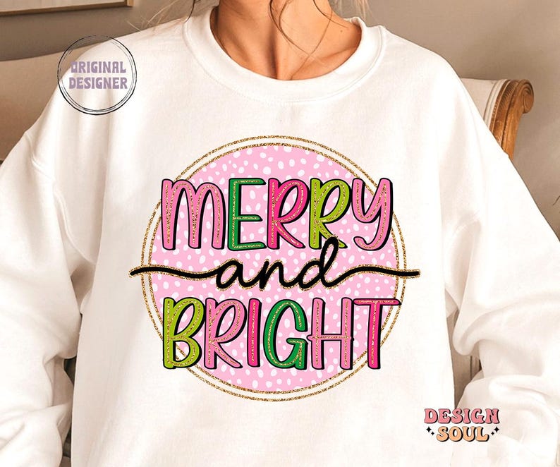 May include: White sweatshirt with a pink polka-dot circle design. The words "MERRY and BRIGHT" are in green and pink lettering, with a gold glitter outline. The words are separated by a black line. The sweatshirt has the text "ORIGINAL DESIGNER" and "DESIGN SOUL" on it.