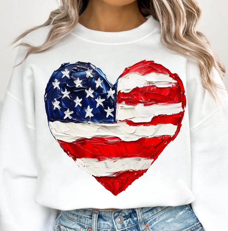 Pu&ograve; includere: Felpa bianca con un design a forma di cuore di bandiera americana dipinta di rosso, bianco e blu.